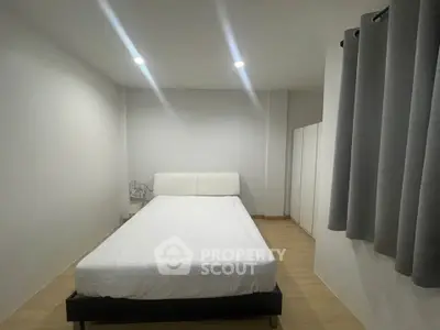 Minimalist bedroom with white bed and modern decor, perfect for a serene living experience.