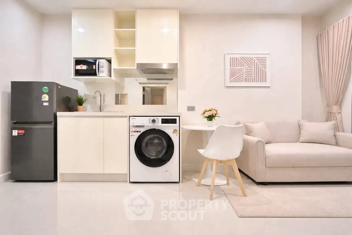 Modern compact kitchen with washing machine and cozy living area in stylish apartment.