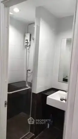 Compact modern bathroom with shower and sink in sleek design.