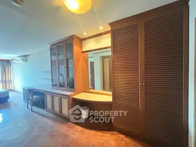 Spacious living area with built-in wooden cabinets and parquet flooring