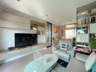 Luxurious living room with modern decor and large TV, perfect for relaxation and entertainment.