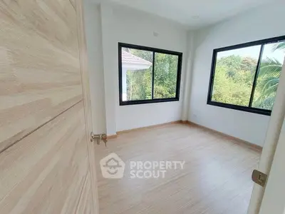 Bright and airy bedroom with large windows and serene garden view, perfect for relaxation.