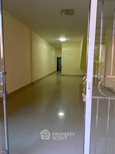 Spacious empty room with glossy floors and open entrance, ideal for customization.
