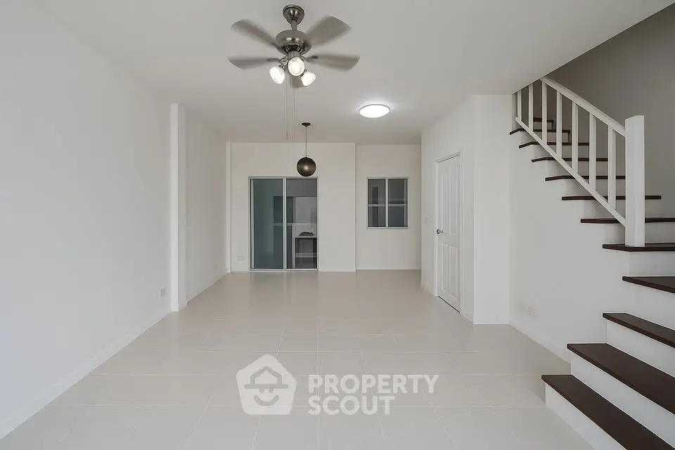 Spacious open-plan living room with modern staircase and ceiling fan