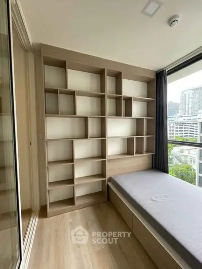 Modern bedroom with built-in shelving and city view, perfect for urban living.
