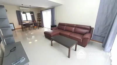 Spacious modern living room with leather sofa and dining area, perfect for family gatherings.