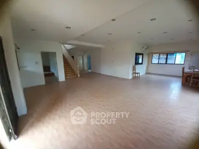 Spacious open-plan living area with tiled flooring and staircase