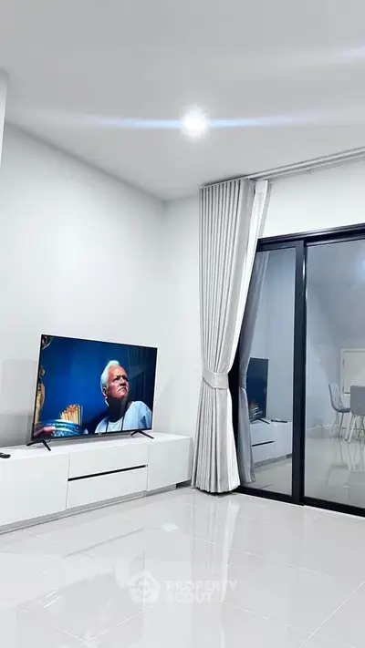 Modern living room with sleek TV setup and large sliding glass doors.