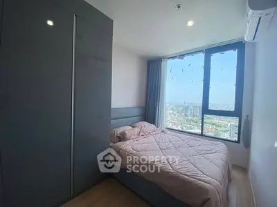 Modern bedroom with large window offering stunning city view and sleek wardrobe.