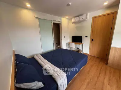 Modern bedroom with wooden flooring, sliding door, and air conditioning unit.