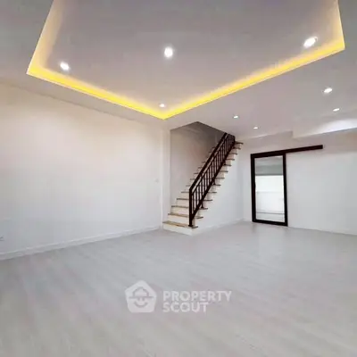 Spacious modern living room with elegant staircase and recessed lighting