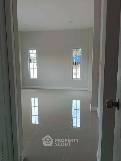 Spacious empty room with glossy tiled floor and large windows
