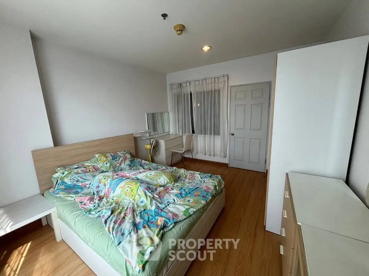 Spacious bedroom with wooden flooring and modern furniture