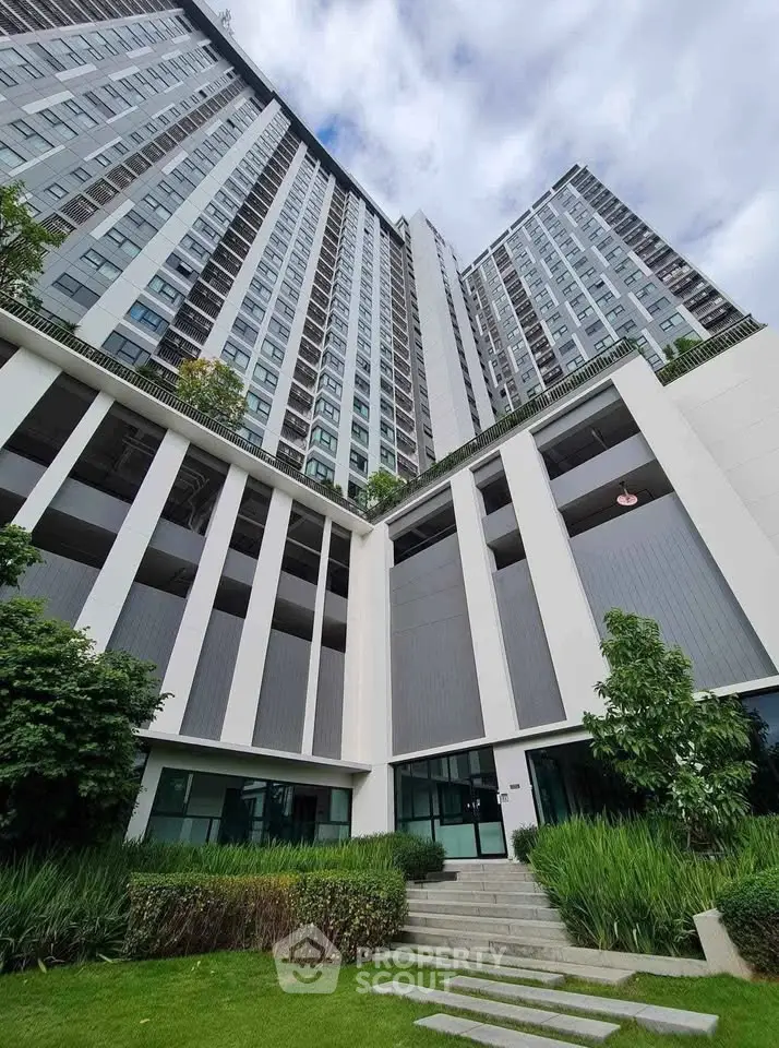 Modern high-rise building with lush landscaping and contemporary architecture.
