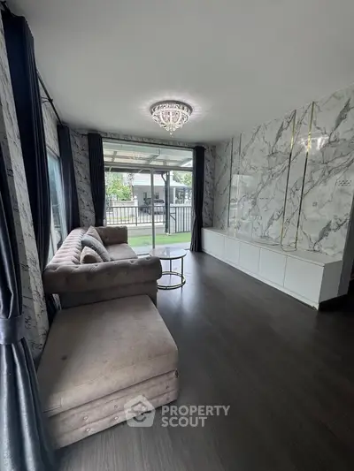 Luxurious living room with elegant marble walls and plush sofa, overlooking a serene garden view.
