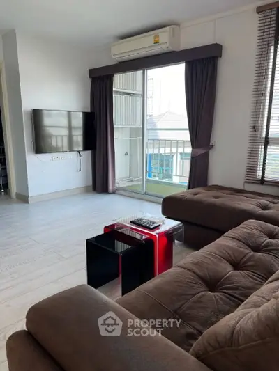Spacious living room with modern furniture and balcony view in urban apartment.
