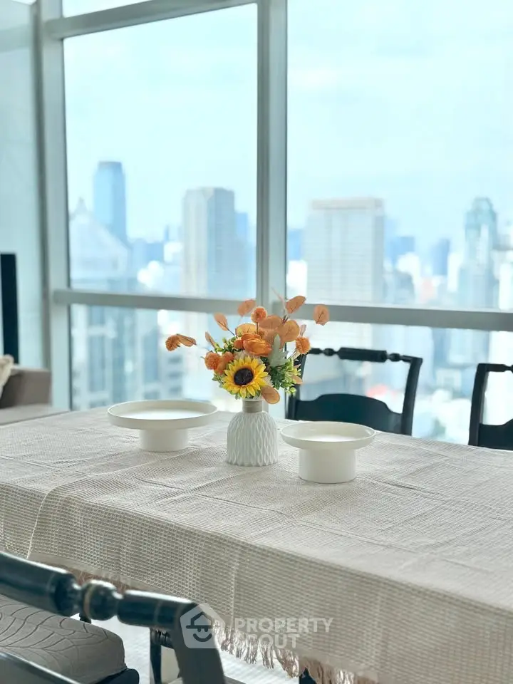 Elegant dining area with city view, featuring a stylish table setting and large windows.