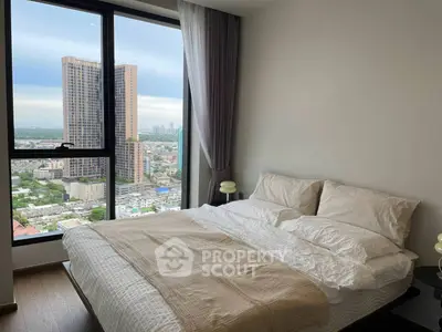 Modern bedroom with large window offering stunning city view in high-rise apartment.