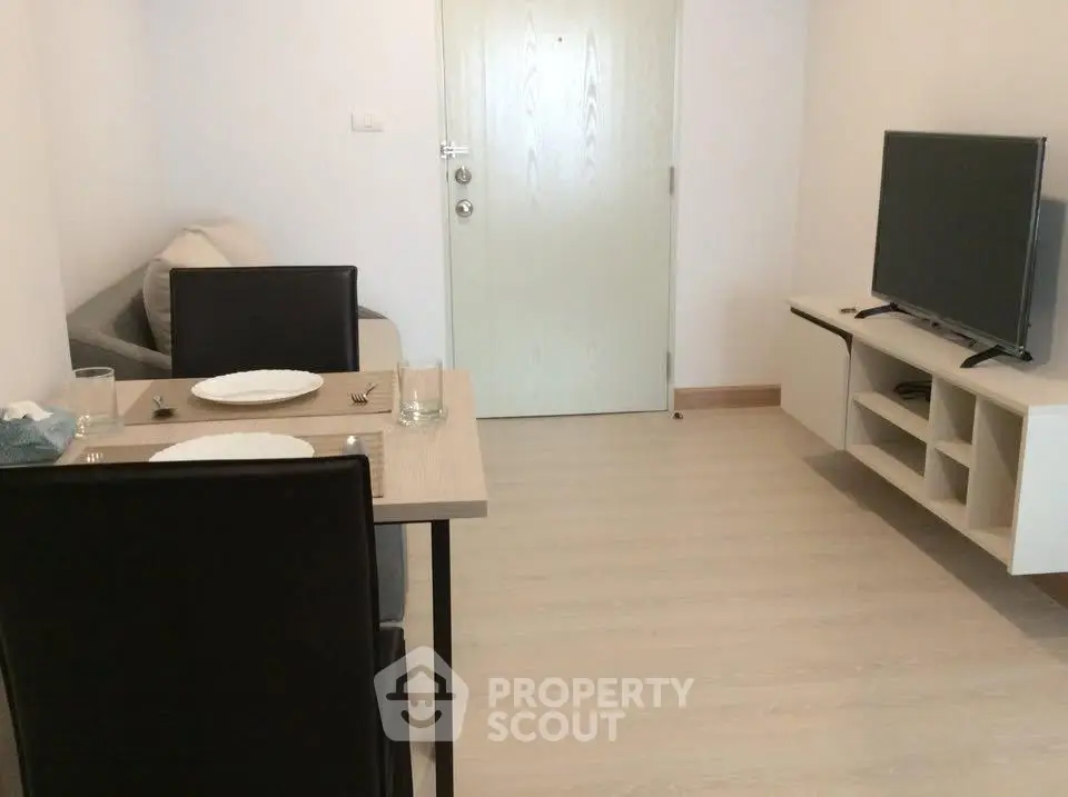 Cozy living room with dining area and modern TV setup in a compact apartment.