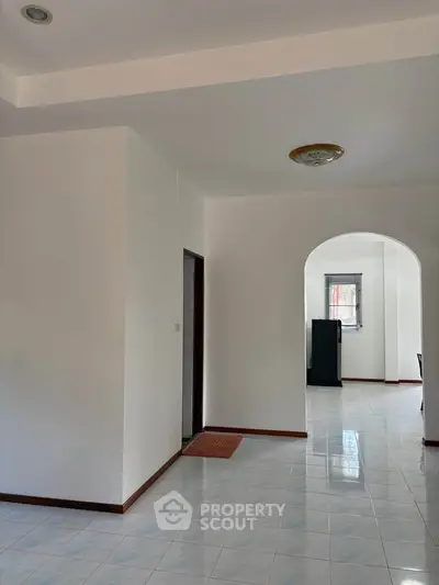Spacious interior with tiled flooring and arched doorway, perfect for modern living.