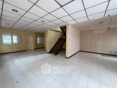 Spacious open-plan interior with tiled flooring and staircase, ideal for customization.