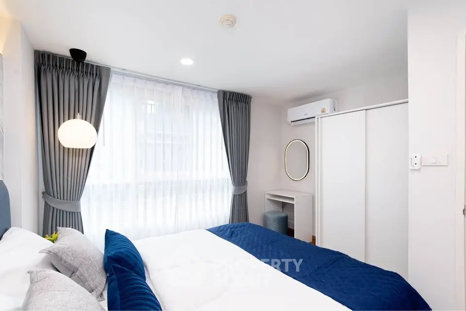 Modern bedroom with stylish decor, featuring a cozy bed, elegant curtains, and a sleek air conditioning unit.