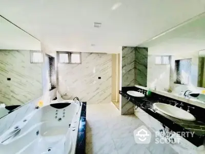 Luxurious spacious bathroom with marble tiles, large jacuzzi tub, and dual vanity sinks, perfect for a rejuvenating experience.