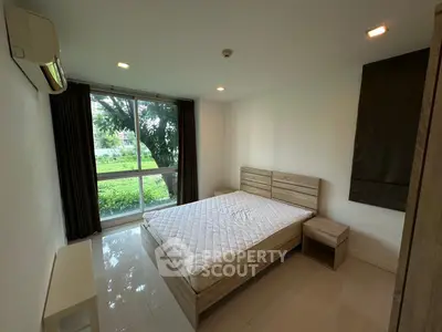 Bright bedroom with large window and garden view, featuring modern wooden bed and nightstand.