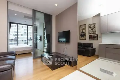 Modern apartment interior with open living room and bedroom view, featuring sleek furniture and large windows.