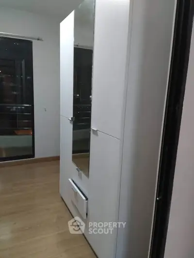 Modern wardrobe in a sleek bedroom with wooden flooring and balcony view.