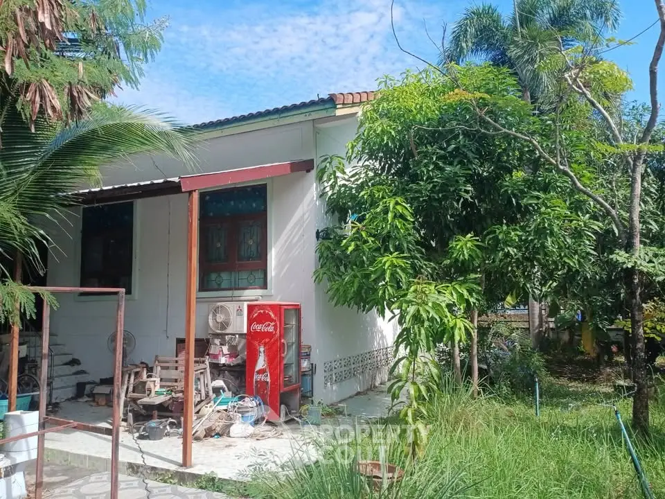 Charming tropical home with lush garden and vintage Coca-Cola vending machine.