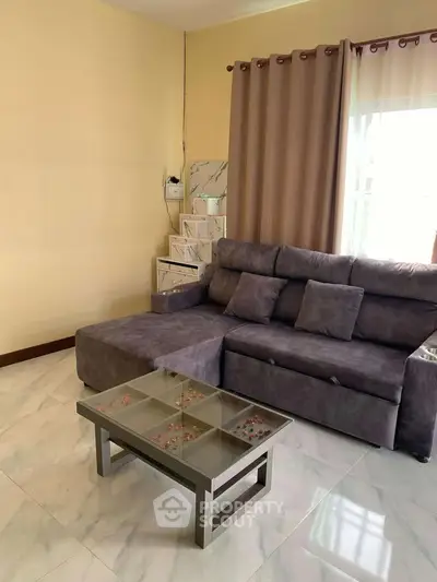 Modern living room with plush gray sofa and sleek glass coffee table.