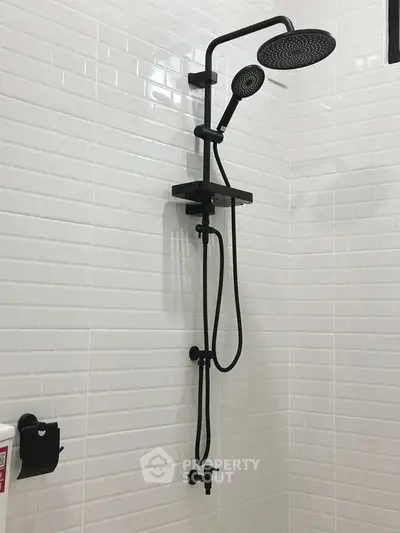 Modern bathroom shower with sleek black fixtures and white tile wall.