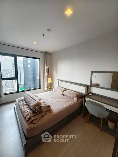 Modern bedroom with city view, stylish furniture, and ample natural light.