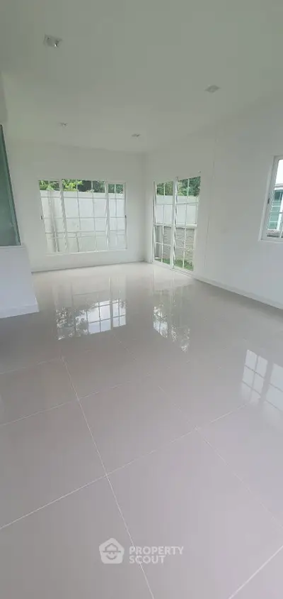 Spacious and bright empty room with large windows and glossy tiled floor