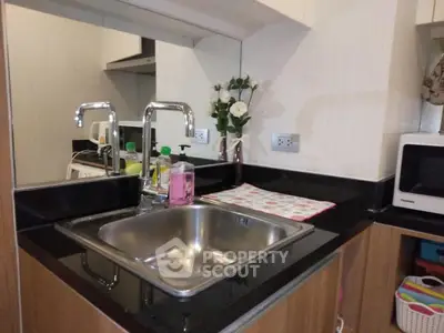 Modern kitchen with sleek sink and countertop, featuring a microwave and stylish decor.