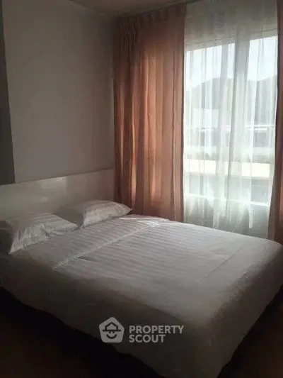 Cozy bedroom with natural light and elegant curtains, perfect for relaxation.