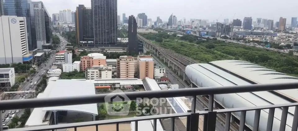 Stunning cityscape view from a high-rise balcony overlooking urban skyline and lush greenery.