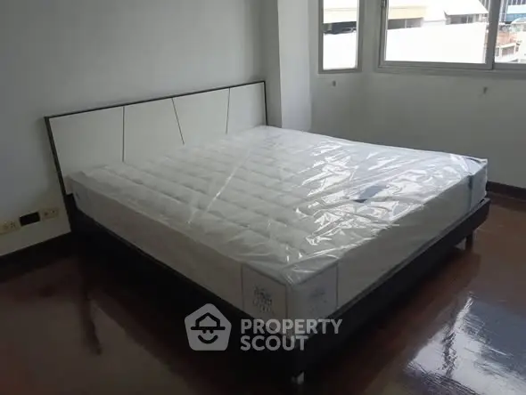 Spacious bedroom with new mattress and large windows offering natural light.