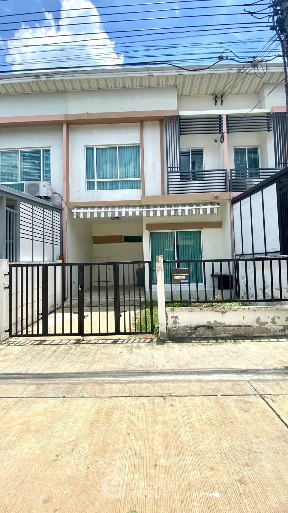 Modern townhouse exterior with gated entrance and balcony, perfect for urban living.