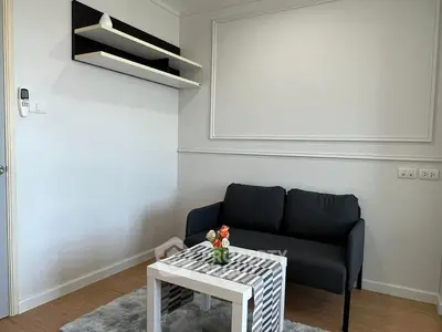 Modern minimalist living room with sleek black sofa and stylish shelves.