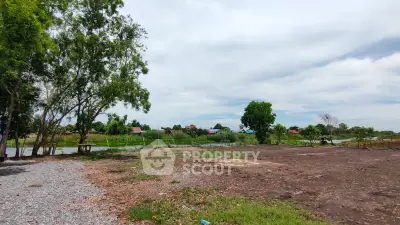 Expansive land plot with lush greenery and serene water view, perfect for development or investment.