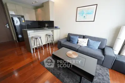 Modern living room with sleek kitchen, hardwood floors, and stylish decor in a cozy apartment.