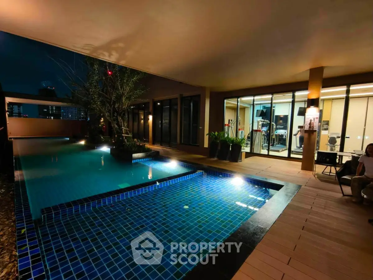 Luxurious condo with illuminated pool and modern gym at night, perfect for relaxation and fitness enthusiasts.