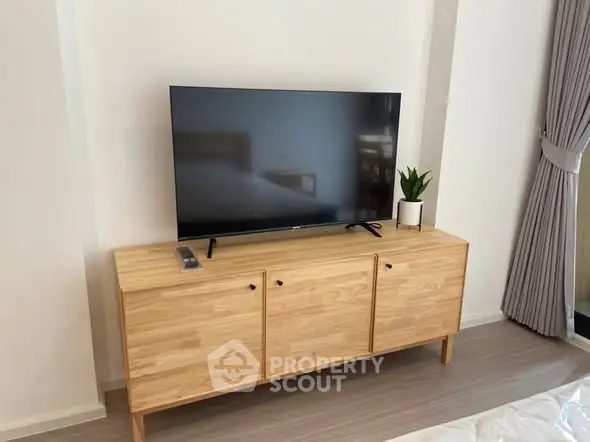 Modern living room with sleek TV setup on wooden cabinet and stylish decor.
