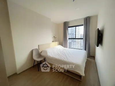 Modern bedroom with large window and minimalist decor in urban apartment.