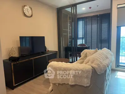 Modern living room with cozy sofa and TV, featuring elegant decor and natural light.