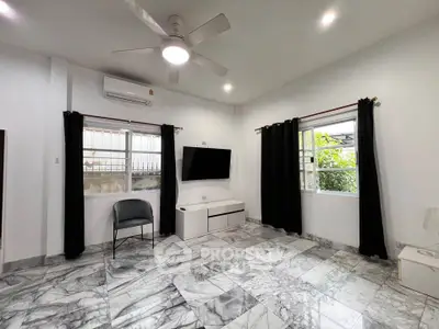 Spacious living room with marble flooring, modern ceiling fan, and large windows for natural light.
