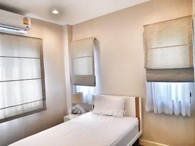 Cozy bedroom with natural light and modern decor, featuring a single bed and air conditioning.