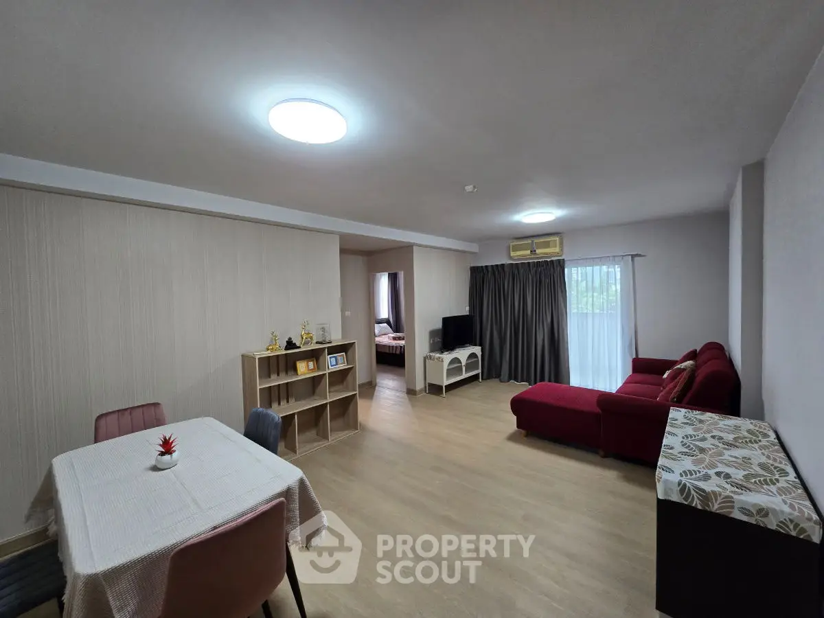 Spacious living room with modern decor and open layout, featuring a cozy red sofa and dining area.